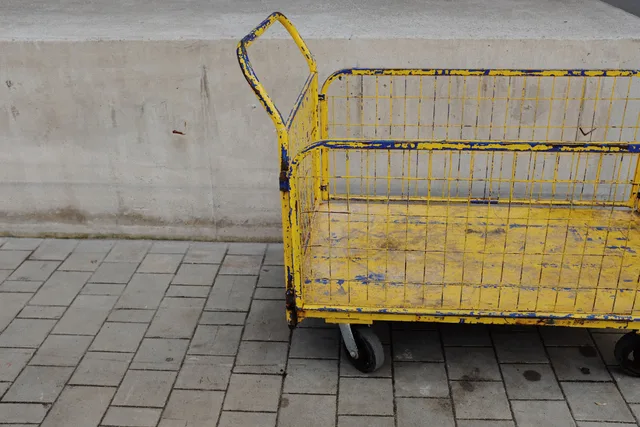 A rustic, yellow utility cart on a paved surface, ideal for transportation and industrial themes. Wedding coordinator equipment: four bags, a cart, and what to buy first